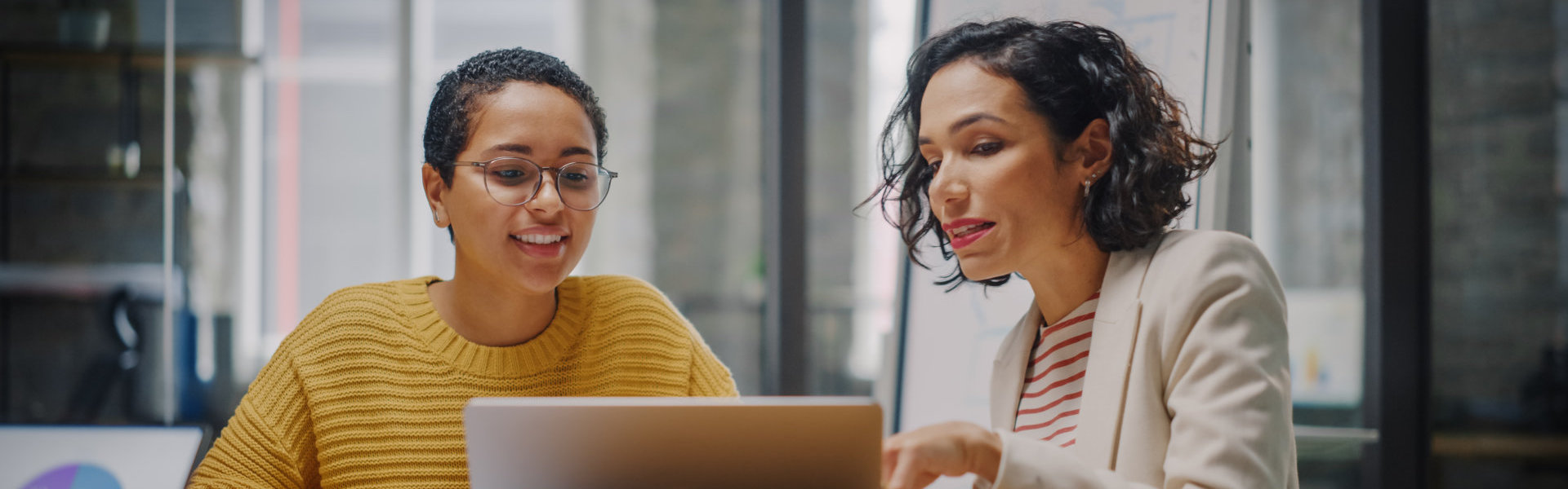 two people talking inside an office with their laptop